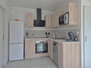 a kitchen with wooden cabinets and a white refrigerator at Ticya Lodge - Maison calme, neuve, proche de Disneyland Paris, parking privé in Isles-lès-Villenoy