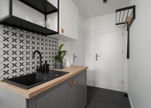 a kitchen with a sink and a black and white tiled wall at Patro Apartament 2 Wrocław Centrum in Wrocław