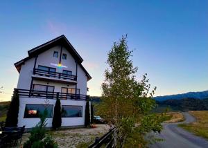 a white house with a balcony on the side of a road at Pensiunea Soarelui in Fundata