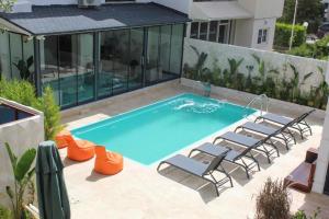 ein Swimmingpool mit Liegestühlen neben einem Haus in der Unterkunft Lara Smart Aparts in Antalya