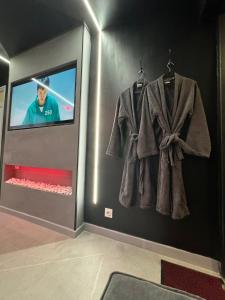 a room with a tv and a robe on a wall at La squid love jacuzzi & cinema prive in Melun