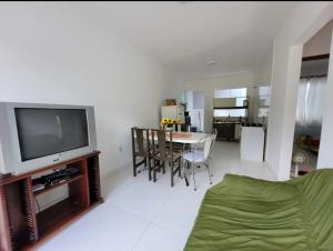 a living room with a television and a table with chairs at Casa de praia com wi-fi in Barra Velha