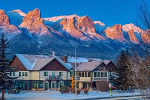 a building in front of a mountain range with snow at Basecamp Lodge Canmore in Canmore