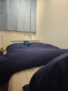 Una cama con un edredón azul en un dormitorio. en London Serviced Accommodation x RM10 x DM 4 Weekly x Monthly Deals x Sleeps 10 x FREE Parking x FREE Wifi E, en Dagenham
