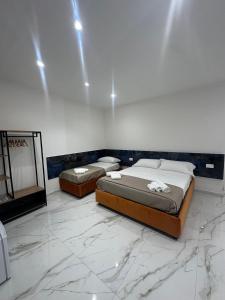 two beds in a room with marble floors and a mirror at Emerald Rooms in Naples