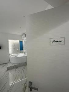 a white bathroom with a tub and a sink at Emerald Rooms in Naples