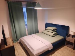 a bedroom with a bed with a blue headboard and a window at Apartament Nou 2 camere Slatina in Slatina