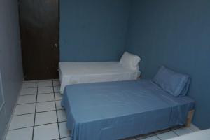 two beds in a small room with blue walls at Habitación con tres camas in Tonalá