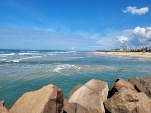 a view of a beach with rocks in the water at Apto Belle Residencial Ilha Bela in Passo de Torres