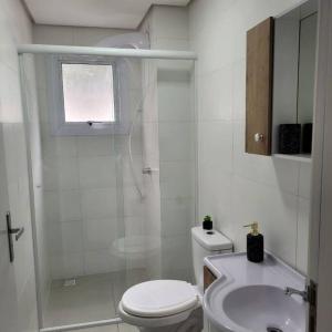 a white bathroom with a toilet and a sink at Apto Belle Residencial Ilha Bela in Passo de Torres