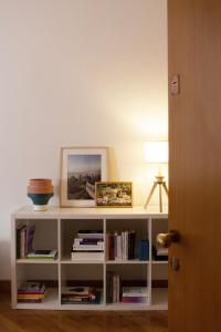 a white book shelf with books and a picture at Appartamento moderno e tranquillo in Piacenza