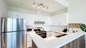 a kitchen with white cabinets and a stainless steel refrigerator at Stunning 1-Bedroom Condo in the Heart of Vancouver in Vancouver