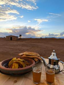 un vassoio di cibo su un tavolo con una teiera e un piatto di banane di Silent Camp a M'Hamid