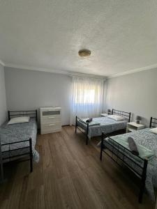 a room with three beds in a room with wooden floors at Boa Sorte 13 in Costa de Lavos