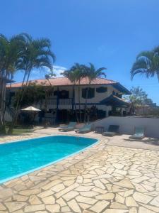 ein Schwimmbad mit Stühlen und ein Haus in der Unterkunft Pousada in Bombinhas