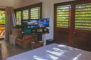 a bedroom with a bed and a tv and a couch at Naquela Casa Jericoacoara in Jericoacoara