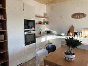 a kitchen with white cabinets and a wooden table at Lodge évasion Lot & Dordogne in Masclat