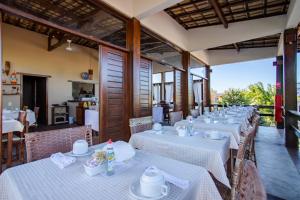 a row of tables in a restaurant with white linens at Naquela Casa Jericoacoara in Jericoacoara