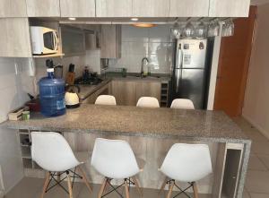 a kitchen with white chairs and a counter top at Quebrada de la Candelaria III in Algarrobo