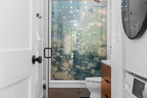 a bathroom with a toilet and a glass shower door at KOTI Vacation Rentals in Williamsburg +31 photos