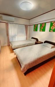 two beds in a room with green banners on the wall at HYGGE HOUSE Tabibitonoie - Vacation STAY 33409v in Kashiwa