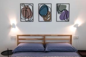 a bedroom with a bed with four pictures on the wall at Appartamenti Aurelia 89 in Nardò