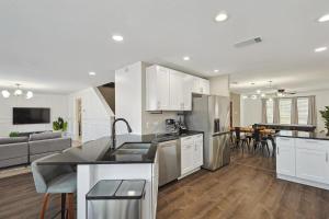a kitchen with white cabinets and a living room at Modern Comforts & Classic Charm w Pool 5BD in Saginaw
