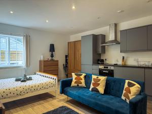 a living room with a blue couch and a kitchen at Apart Hotel Prime Maidstone Location in Maidstone