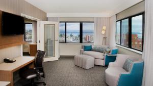 a hotel room with a desk and a chair and a couch at Courtyard by Marriott Seattle Everett Downtown in Everett