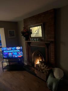 a living room with a fireplace with a tv and a fire at Splash Cottage beach house with Sea lapping Garden in Bangor