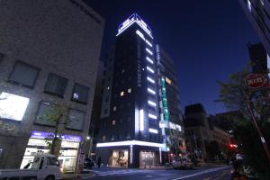 HOTEL LiVEMAX Higashi Ginza في طوكيو: مبنى طويل وبه أضواء عليه في شارع المدينة