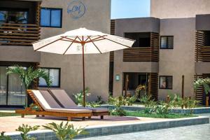 a chair with an umbrella next to a pool at Flat Patacho - Rota Ecológica dos Milagres in Pôrto de Pedras