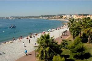 people on a beach with a boat in the water at Appartement T3 Cagnes sur Mer in Cagnes-sur-Mer