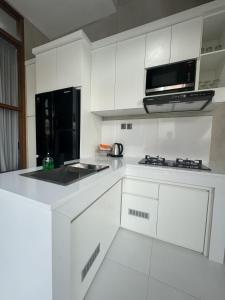 a kitchen with white cabinets and a black microwave at Pandawa House Bali in Uluwatu +19 photos