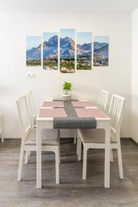 a white dining room table with four chairs and a painting at Apartma pri lipi in Bohinj