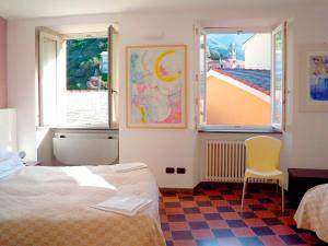 a bedroom with a bed and two windows and a chair at Hotel Gianni Franzi in Vernazza