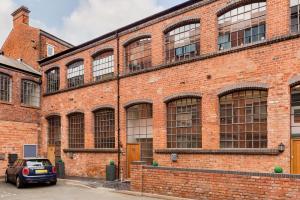 a brick building with a car parked in front at High End Luxury Townhouse in JQ, 4 Bedrooms, Flat screen TV in all rooms, Free Parking, Near Birmingham City Centre DEPOSIT REQUIRED in Birmingham