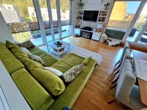 a living room with a green couch and large windows at Waldorf Apartment in Ljubljana +9 photos