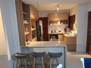 a kitchen with wooden cabinets and a counter with stools at Residencial VillaBella casa 3 Quartos, piscina, na Vila junto ao Centro e Praia in Marau