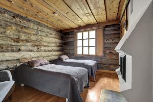 two beds in a room with wooden walls at Bliss Adventure Lodge in Pyhätunturi