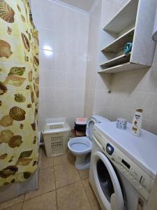 a bathroom with a washing machine and a toilet at Астана аэропорт студия in Prigorodnyy