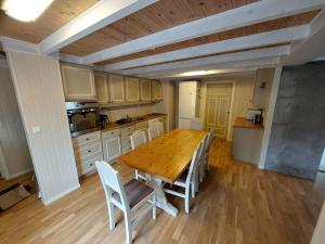a kitchen with a wooden table and white chairs at Jovollstua i Eresfjord med båt til leie in Øverås
