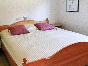 a wooden bed with two purple pillows on it at Amazing holiday home in the nature-By Traum in Laholm