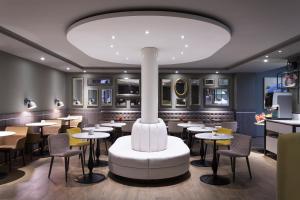 a restaurant with tables and chairs and a large chandelier at Mercure Madrid Centro in Madrid