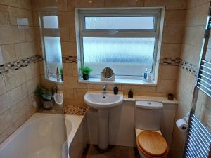 a bathroom with a sink and a toilet and a window at Sunlit garden bungalow in Puriton +23 photos