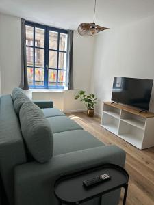 a living room with a couch and a television at L'Escapade Médiévale Appartement neuf in Josselin