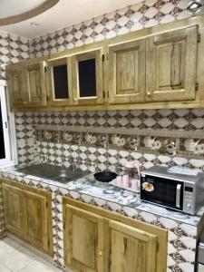 a kitchen with wooden cabinets and a microwave at Appartement meublés in Dakar