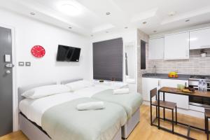 a white bedroom with two beds and a kitchen at Studio9 Rooms - Next to Emirates Stadium - Budget Rooms with Shared Bathroom in London