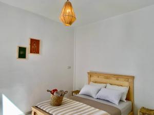 a bedroom with a bed and a basket on a bench at Ocean Surf House in Tamraght Ouzdar