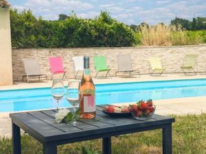 a table with a bottle of wine and a bowl of fruit at Le Mas de mon Père in Villedieu